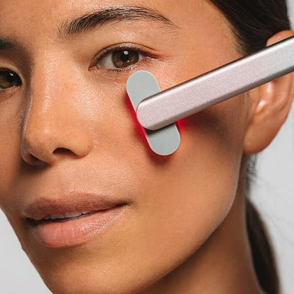 Close-up of a person using a red light therapy wand on their face.
